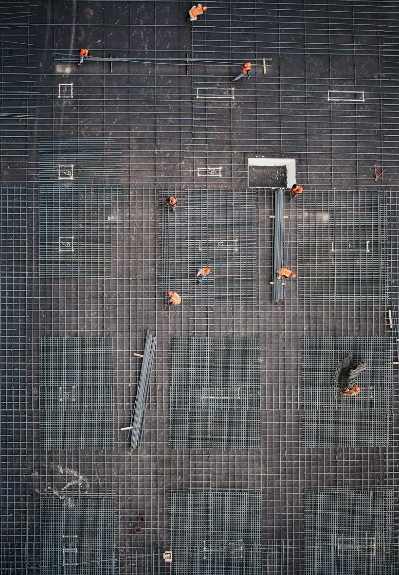 Aerial view of a commercial construction site with crews laying rebar